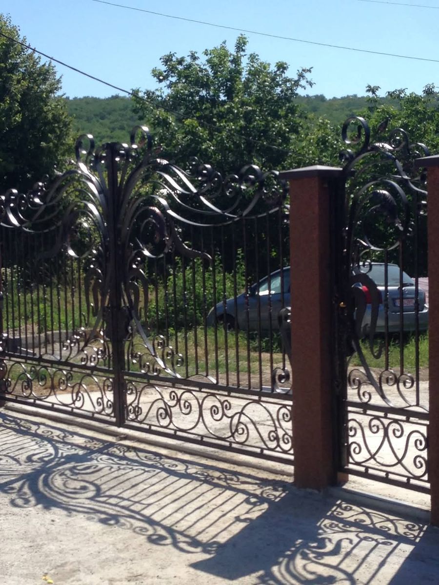 Gard din fier forjat cu volute între stâlpi de cărămidă, lucrare de fier forjat în Vaslui