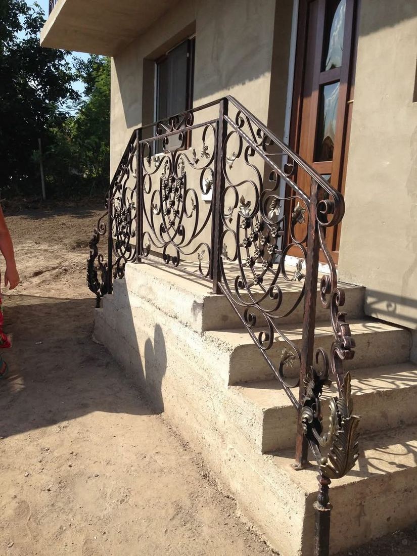 Balustradă exterioară din fier forjat cu volute pe scara de la intrarea unei case