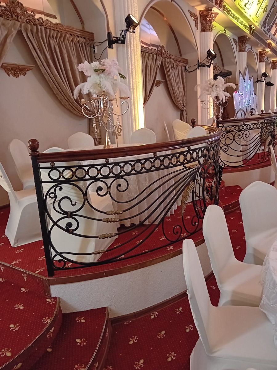 Balustradă din fier forjat cu volute la o sală de evenimente, cu mână curentă din lemn