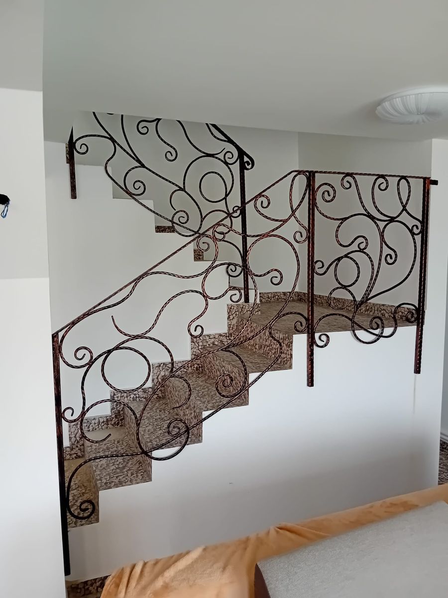 Balustradă din fier forjat cu volute pe o scară interioară cu trepte de granit