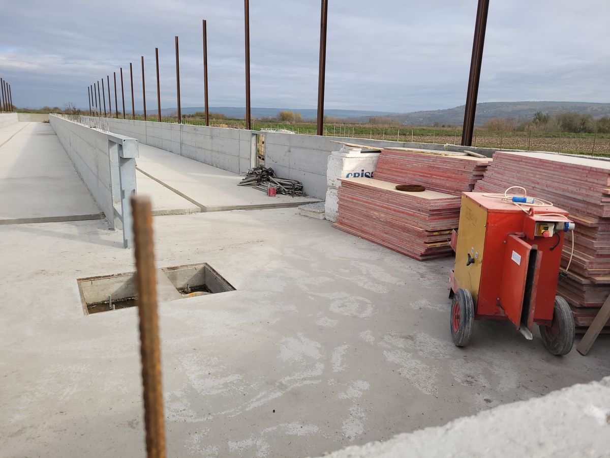 Platformă de beton cu stâlpi metalici și utilaje pe șantierul unei hale