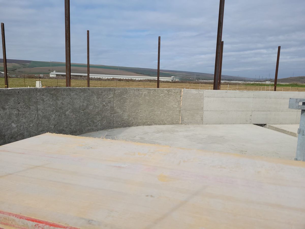 Colț de pereți din beton cu stâlpi metalici pe un câmp, lucrare de structuri metalice