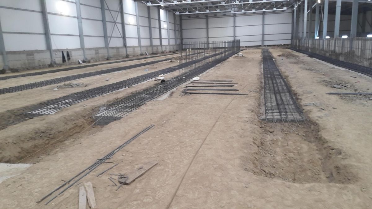 Interiorul unei hale metalice închise, cu armătura pardoselii pregătită