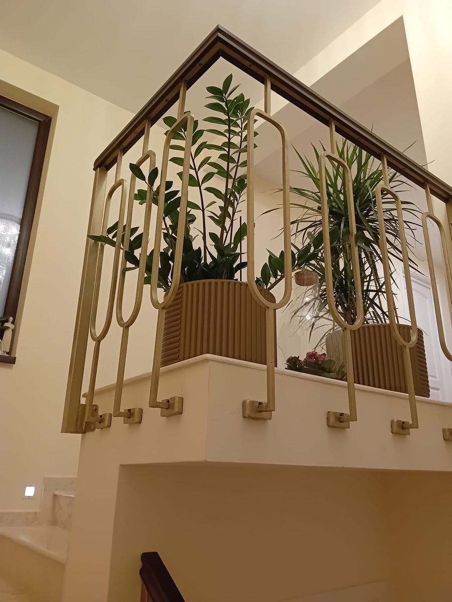 Balustradă metalică modernă aurie pe o scară interioară, cu plante