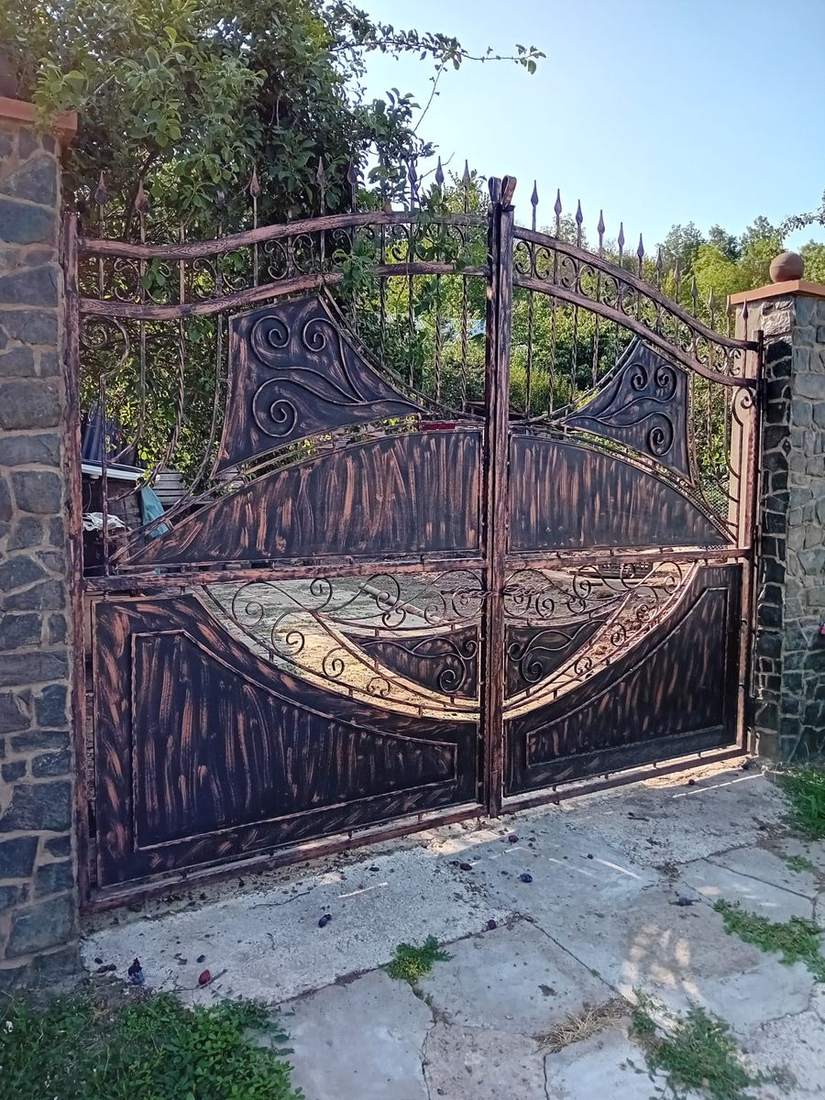 Porți metalice personalizate Vaslui, cu tablă patinată și volute, între stâlpi de piatră